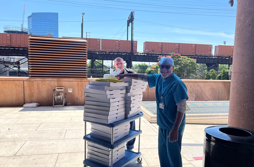Phil Gaspari, director of Operations for Emergency Medicine, left, with Darrell Harris, a medical equipment supply manager, stand by a cart stacked with pizzas.